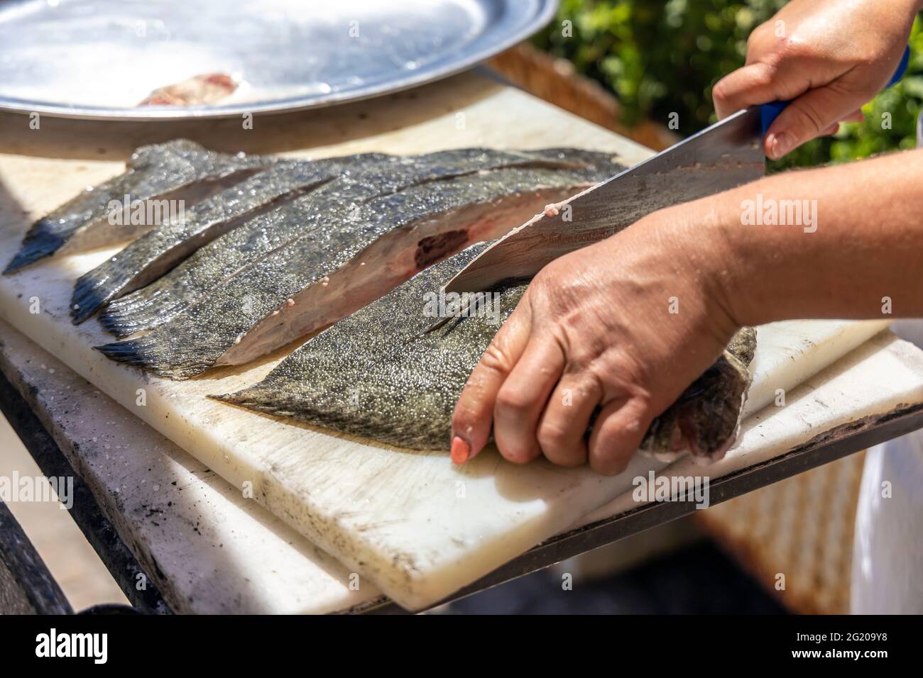 Un cuisinier coupant le poisson à faire cuire au barbecue dans le restaurant portugais Banque D'Images