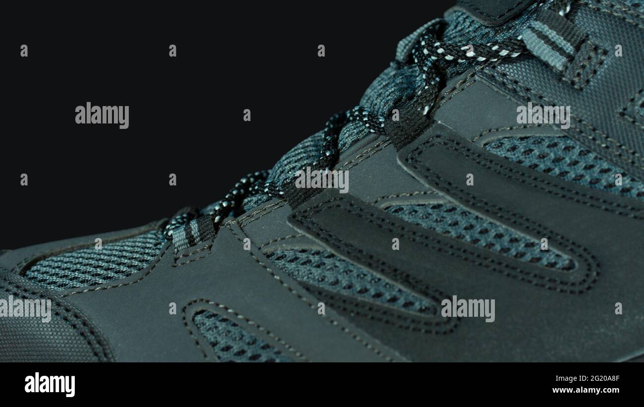 Gros plan sur la partie supérieure d'une chaussure de sport en cuir et tissu gris bleu sur fond noir Banque D'Images
