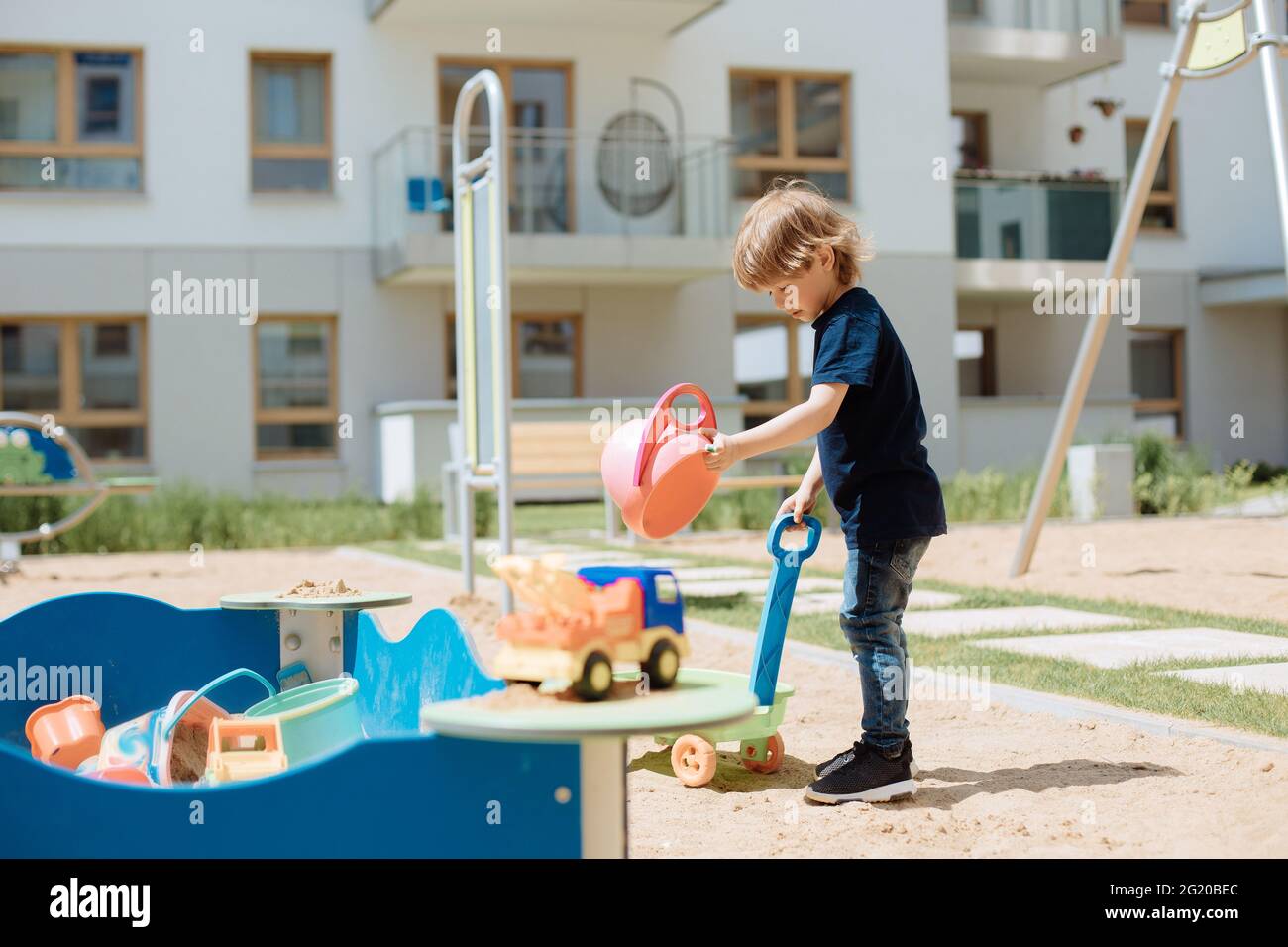 un enfant de 3 ans joue dans une aire de jeux ouverte dans la cour avec des jouets. Concept de loisirs pour enfants Banque D'Images