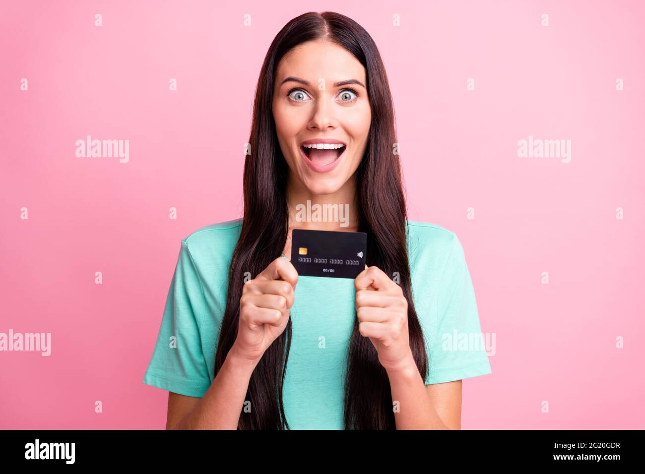 Photo de jeune heureux excité fou souriant étonné surprise fille montrant carte de crédit isolé sur fond rose couleur Banque D'Images