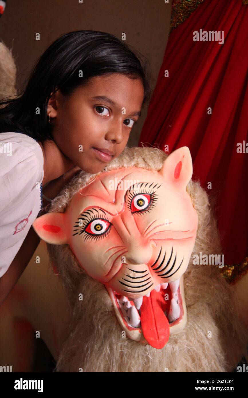 Une jeune fille pose avec le tigre d'argile, la promenade de la Déesse Durga, dans un pandel à Sylhet, au Bangladesh. 1 octobre 2008..dans l'hindouisme, la déesse Durga est adorée comme celle qui peut racheter dans des situations de détresse extrême. Durga ou Maa Durga (mère Durga) est la déesse suprêmement rayonnante décrite comme ayant dix bras, portant un lion ou un tigre, portant des armes et une fleur de Lotus, maintenant un sourire méditatif et pratiquant des « Mudras » ou des gestes symboliques de main. Banque D'Images
