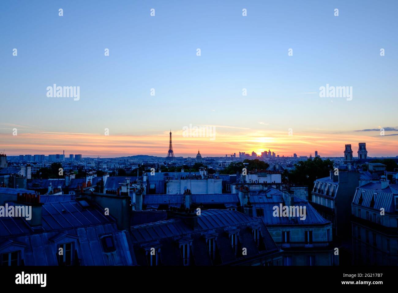 Horizon et toits de Paris au crépuscule le 14 juillet juste avant le grand  feu d'artifice de la journée nationale. Un mélange d'heure bleue et de  coucher de soleil. Le soleil est
