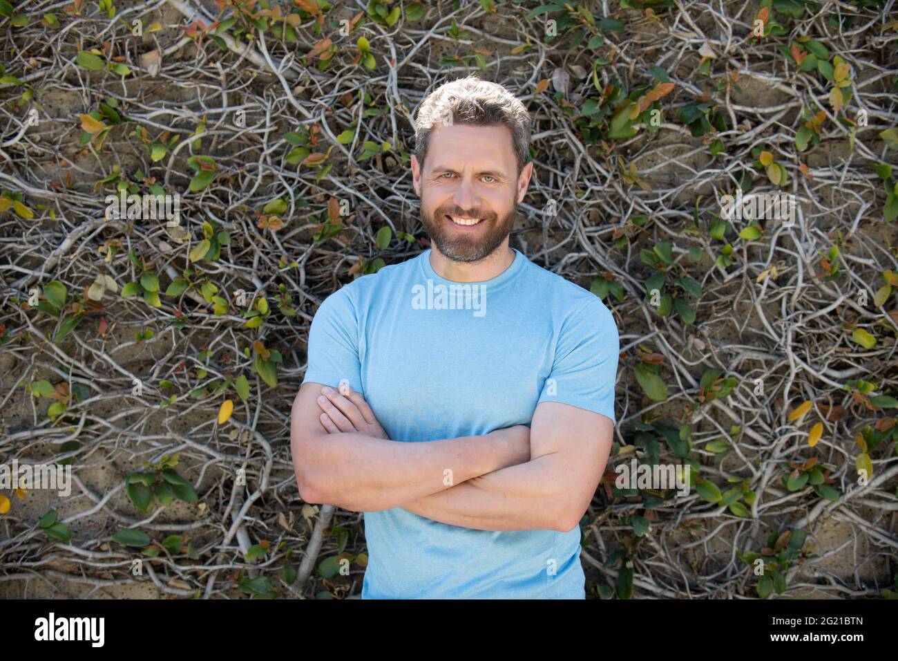 joyeux homme mûr barbu en chemise d'été sur fond de mur de plantes, style d'été Banque D'Images