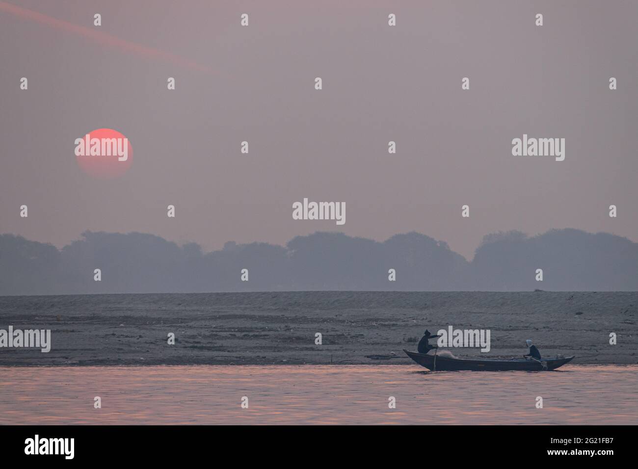 Pêcheurs en silhouette au lever du soleil sur la rivière Ganges à Varanasi, Uttar Pradesh, Inde Banque D'Images