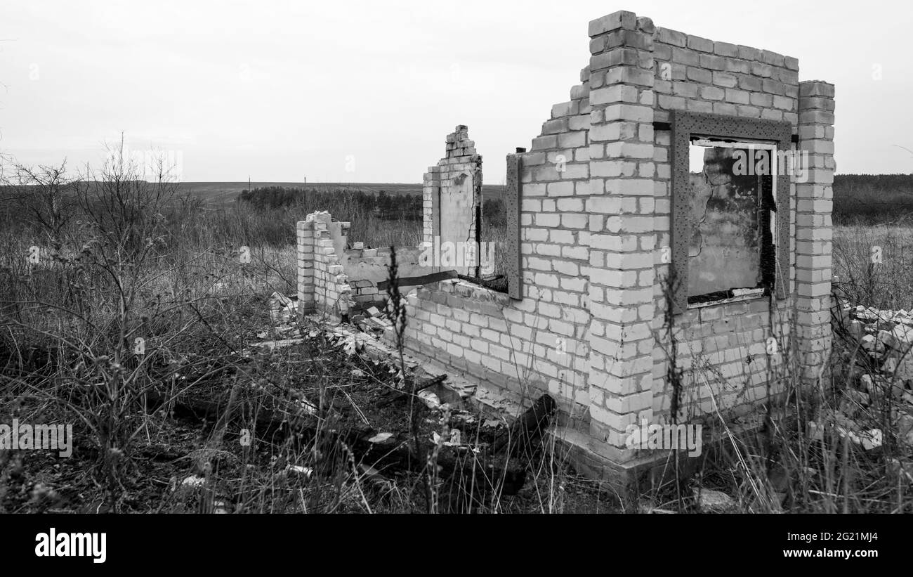 Structure en brique détruite et brûlée avec une fenêtre au bord du champ Banque D'Images