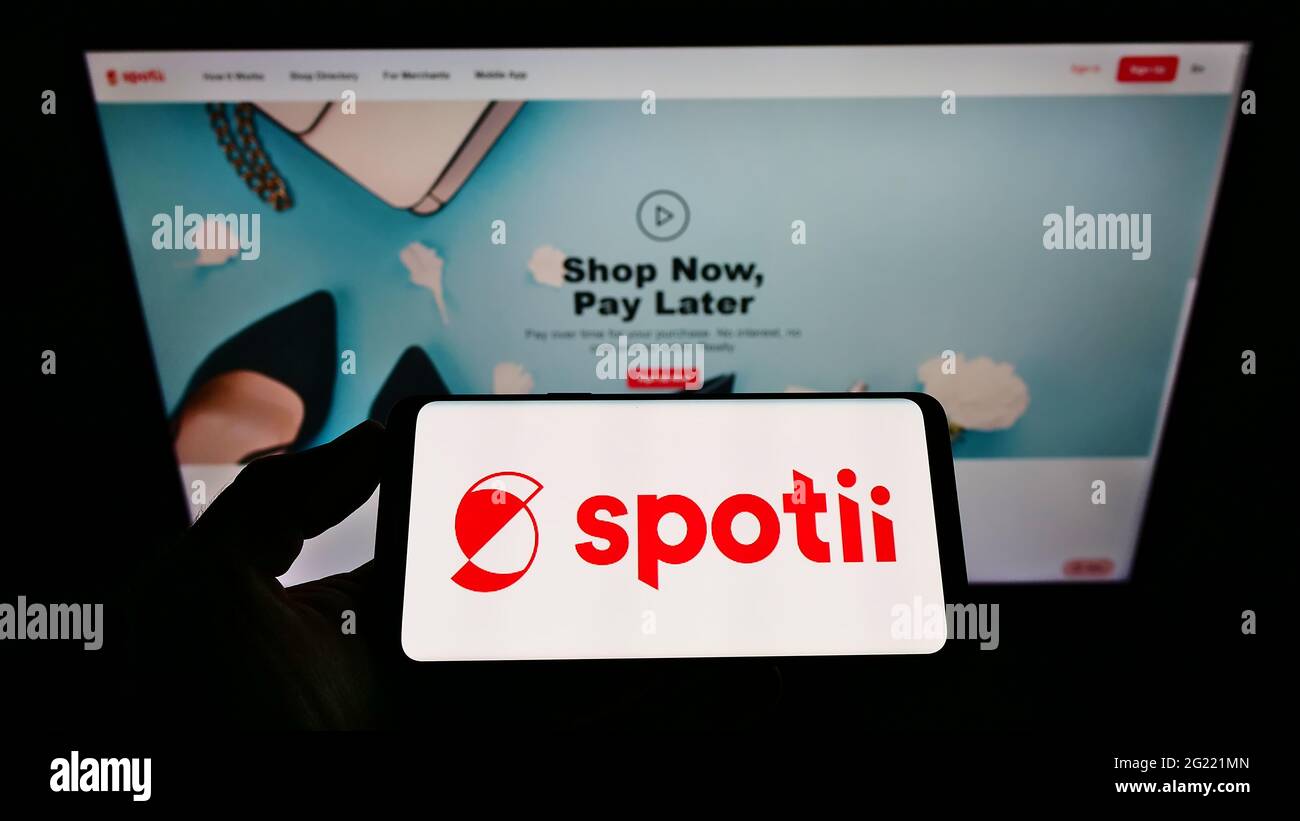 Personne tenant un smartphone avec le logo de la société de plateforme de paiement Spotii DMCC à l'écran devant le site Web. Mise au point sur l'affichage du téléphone. Banque D'Images