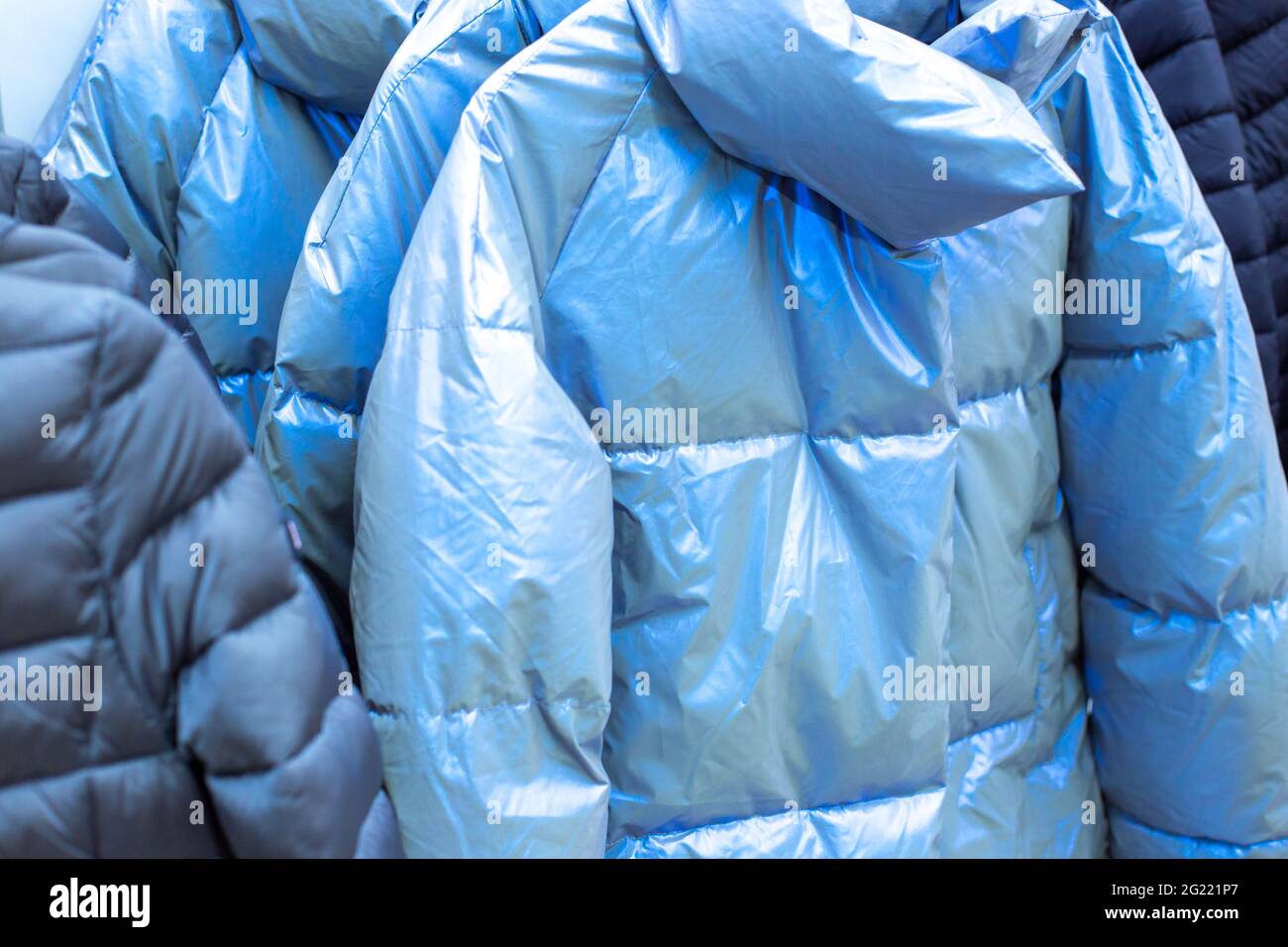 des vestes chaudes de bleu argent clair sont suspendues sur un cintre dans un magasin, vente de vêtements d'hiver Banque D'Images