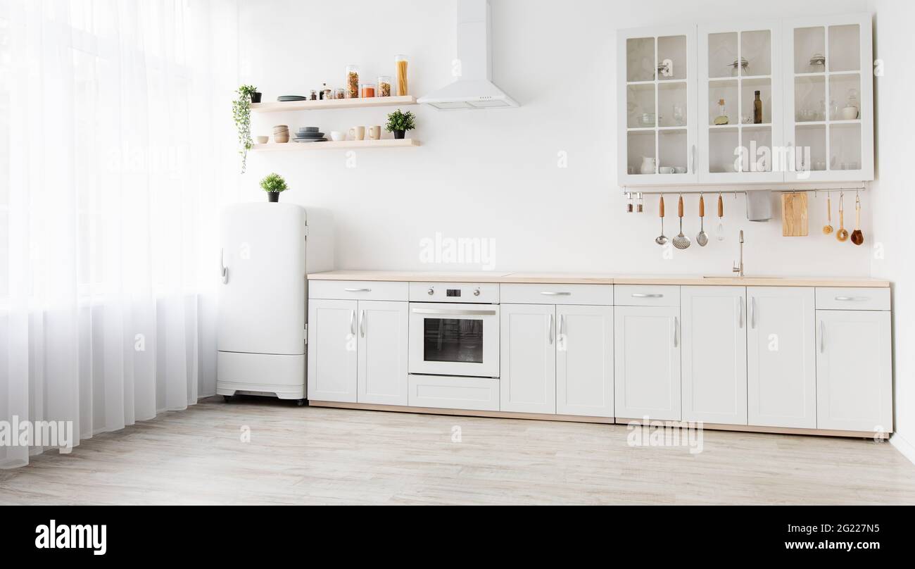 Intérieur scandinave confortable et minimal après réparation. Mobilier de cuisine blanc, réfrigérateur dans la salle à manger simple, panorama Banque D'Images