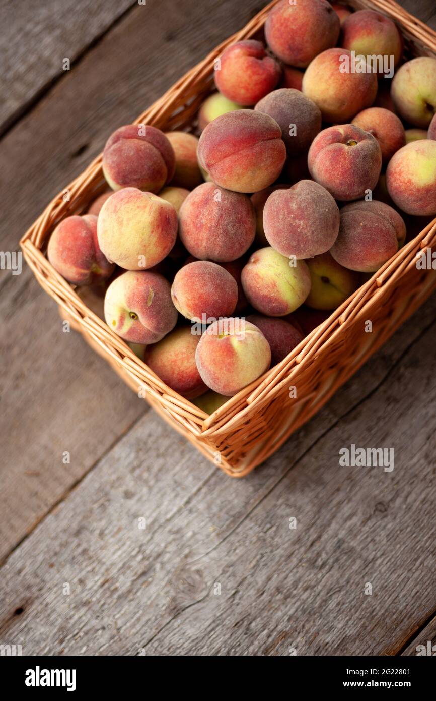 Fruits frais de pêches dans un panier sur fond rustique en bois sombre, vue de dessus.Récolte estivale de fruits.Encore la vie.Un groupe de pêche mûre.Plat Lay repas végétalien.Copier l'espace. Banque D'Images