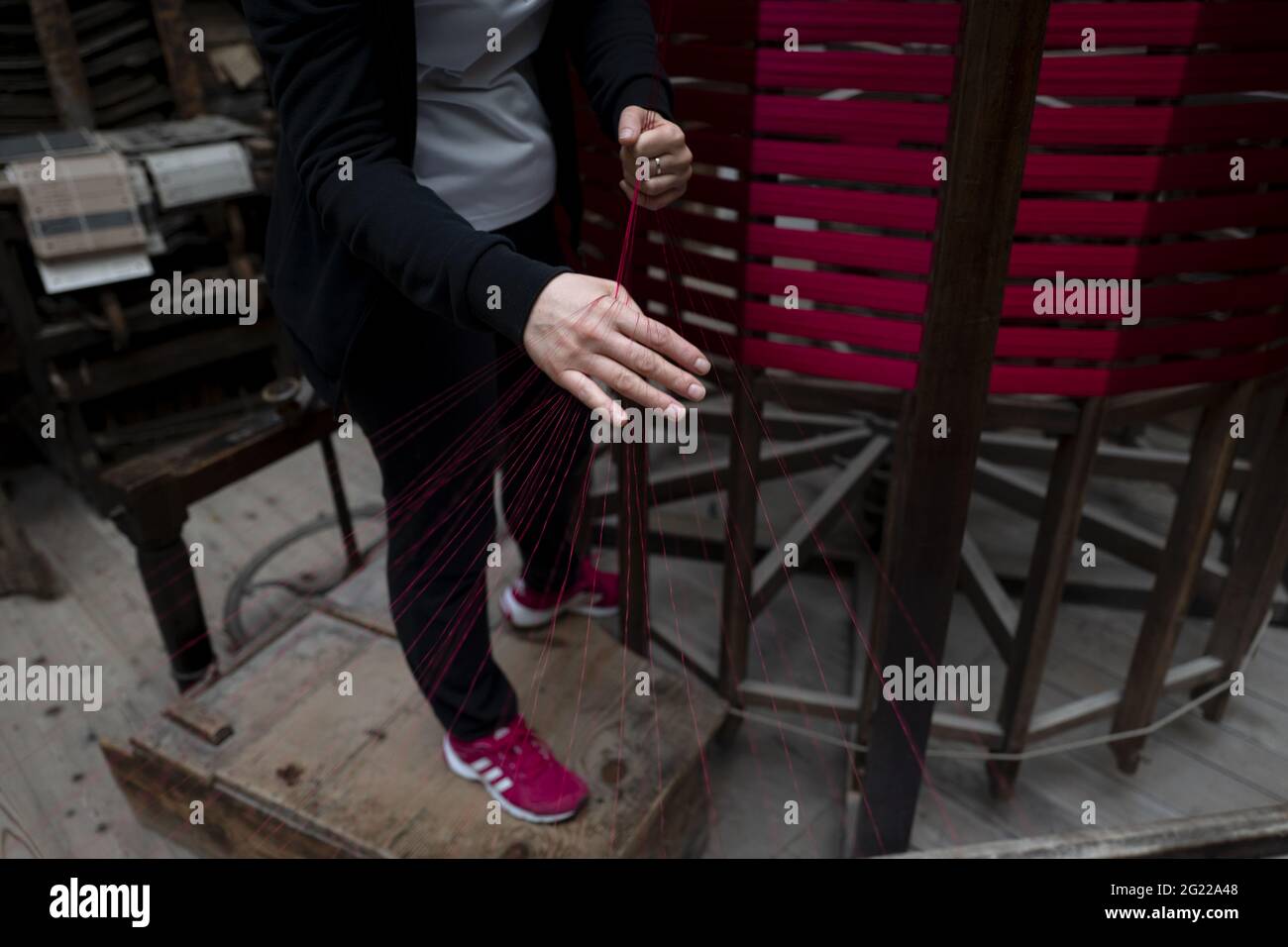 Gros plan sur les mains d'une travailleuse tenant un fil d'or, au tissage artisanal historique Luigi Bevilacqua, à Venise, en Italie Banque D'Images