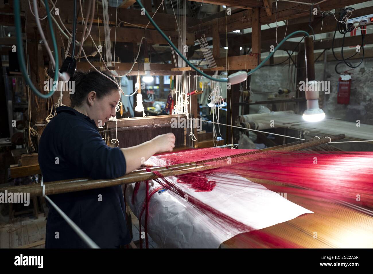 Une travailleuse au tissage fait à la main historique Luigi Bevilacqua, ils produisent des tissus fins pour le mobilier et la haute mode, à Venise, en Italie Banque D'Images