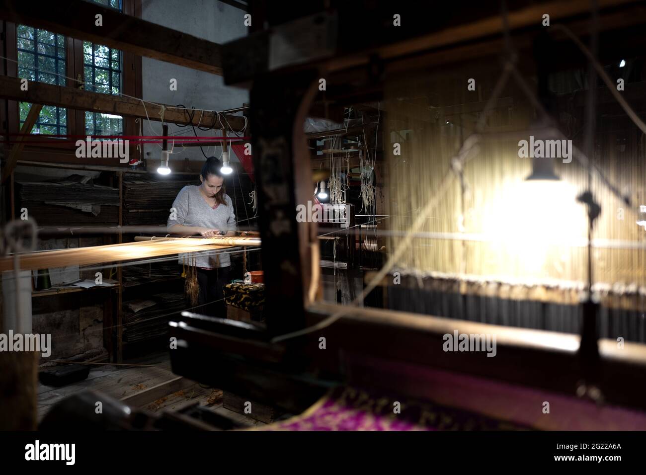 Une travailleuse au tissage fait à la main historique Luigi Bevilacqua, ils produisent des tissus fins pour le mobilier et la haute mode, à Venise, en Italie Banque D'Images