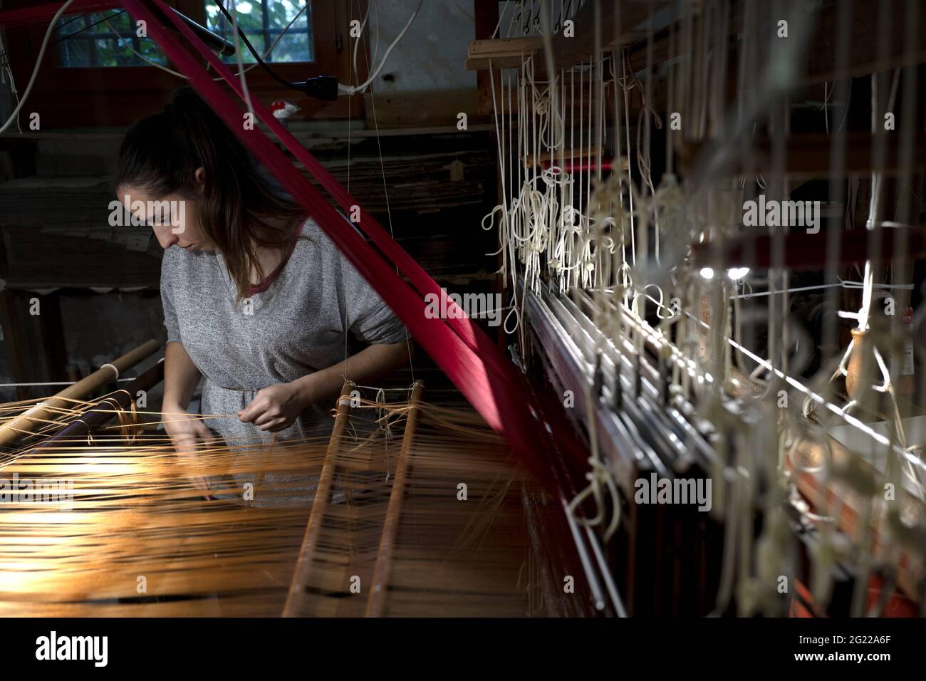Une travailleuse au tissage fait à la main historique Luigi Bevilacqua, ils produisent des tissus fins pour le mobilier et la haute mode, à Venise, en Italie Banque D'Images