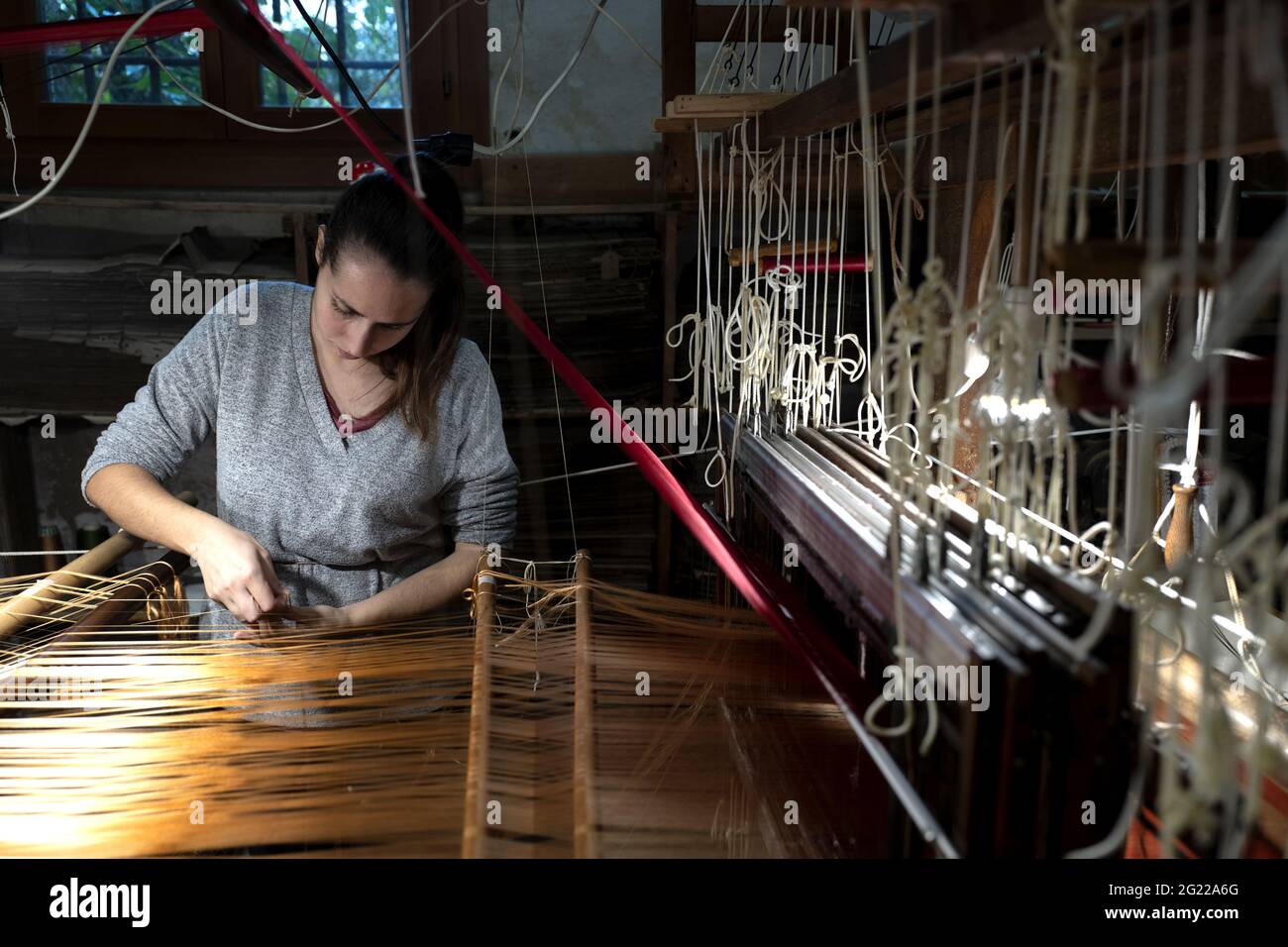 Une travailleuse au tissage fait à la main historique Luigi Bevilacqua, ils produisent des tissus fins pour le mobilier et la haute mode, à Venise, en Italie Banque D'Images