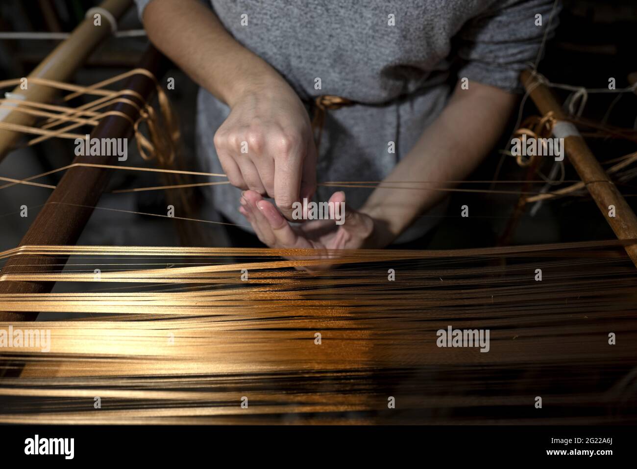 Gros plan sur les mains d'une travailleuse tenant un fil d'or, au tissage artisanal historique Luigi Bevilacqua, à Venise, en Italie Banque D'Images