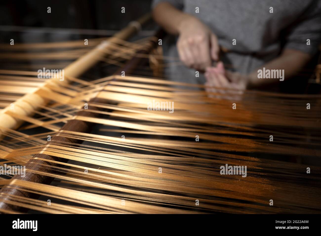 Gros plan sur les mains d'une travailleuse tenant un fil d'or, au tissage artisanal historique Luigi Bevilacqua, à Venise, en Italie Banque D'Images