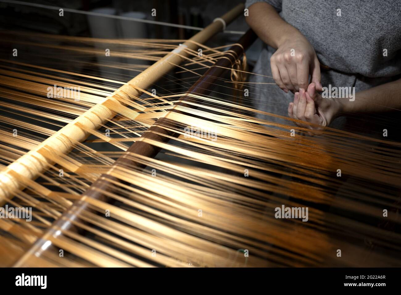 Gros plan sur les mains d'une travailleuse tenant un fil d'or, au tissage artisanal historique Luigi Bevilacqua, à Venise, en Italie Banque D'Images