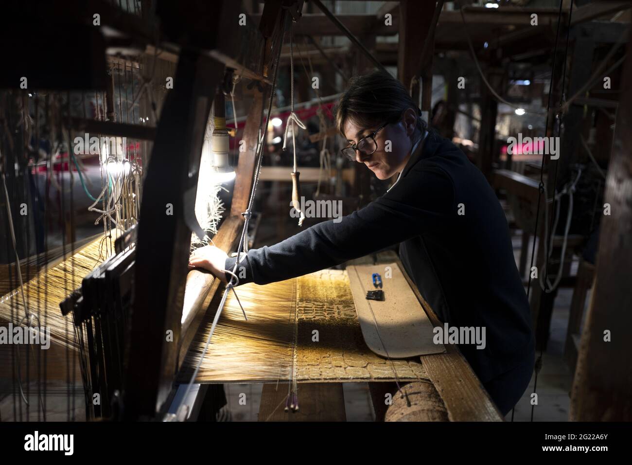 Une travailleuse au tissage fait à la main historique Luigi Bevilacqua, ils produisent des tissus fins pour le mobilier et la haute mode, à Venise, en Italie Banque D'Images