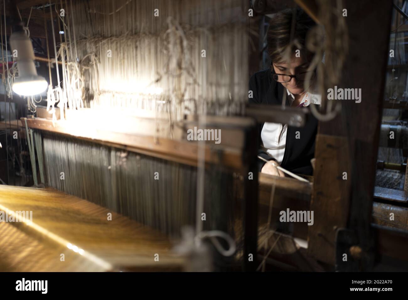 Une travailleuse au tissage fait à la main historique Luigi Bevilacqua, ils produisent des tissus fins pour le mobilier et la haute mode, à Venise, en Italie Banque D'Images