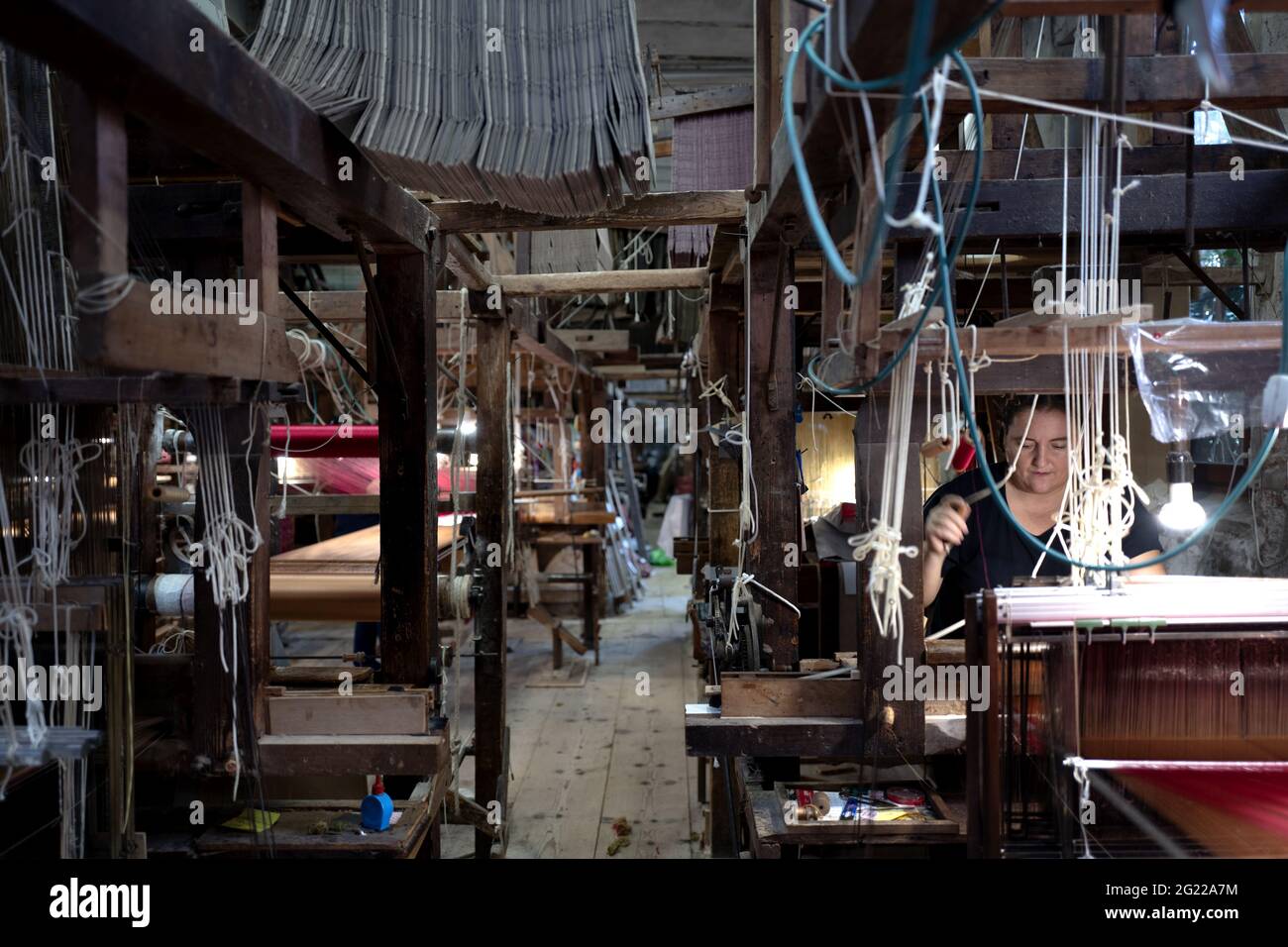 Une travailleuse au tissage fait à la main historique Luigi Bevilacqua, ils produisent des tissus fins pour le mobilier et la haute mode, à Venise, en Italie Banque D'Images