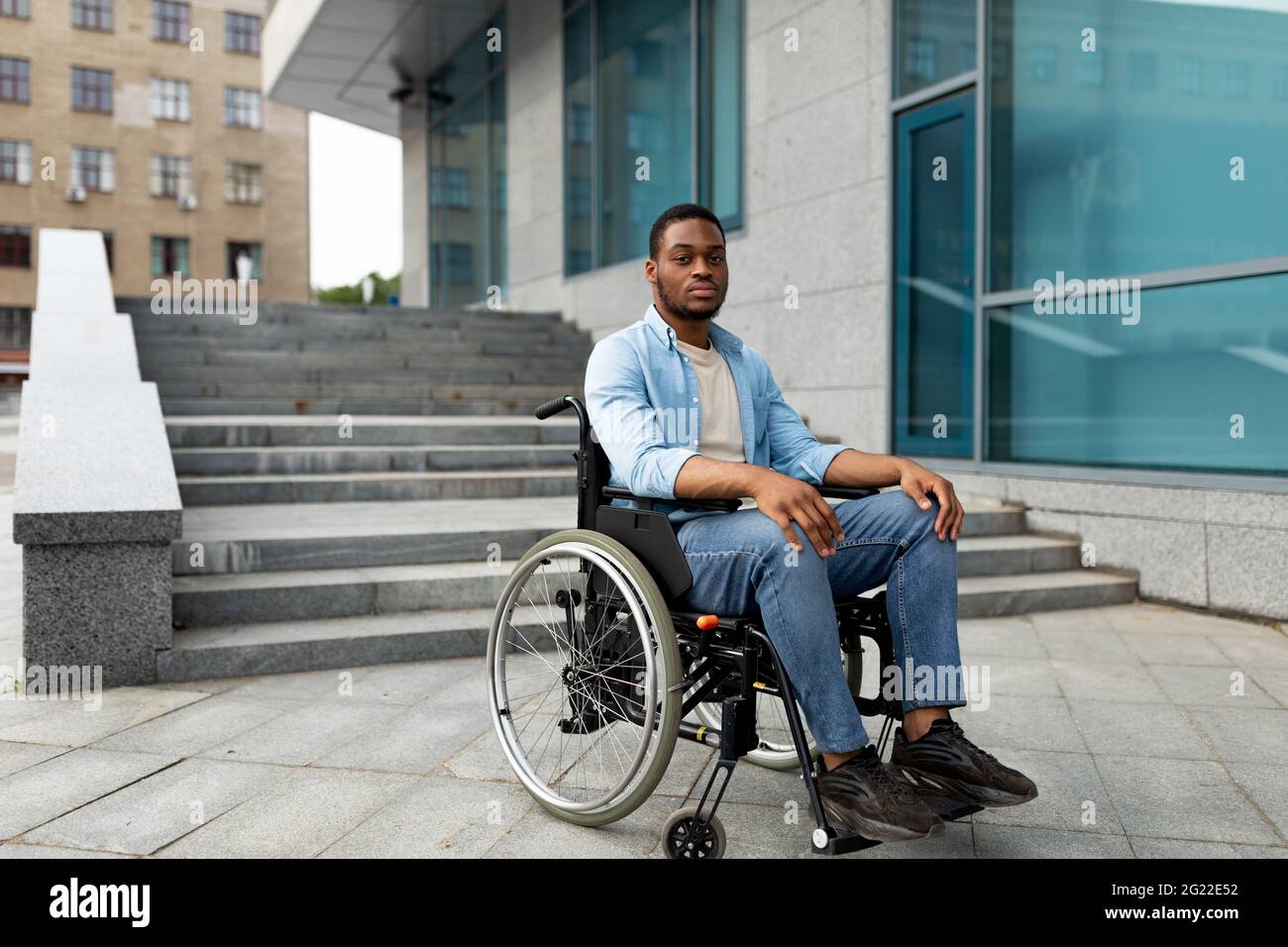 Portrait d'un malheureux homme noir malheureuse en fauteuil roulant à côté de siatrs sans rampe, se sentir stressé, espace libre Banque D'Images