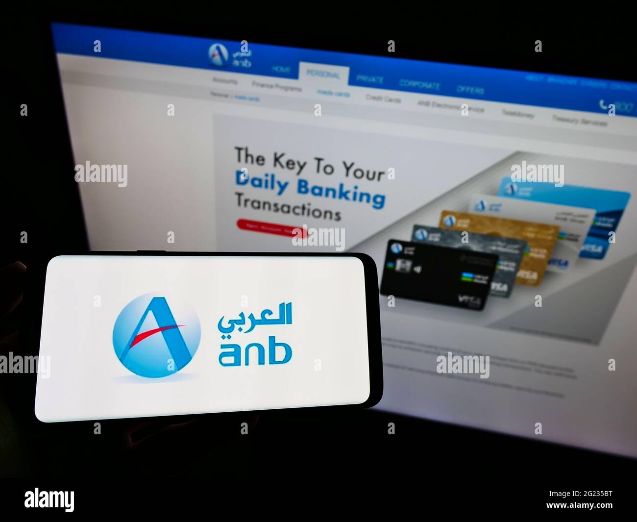 Personne tenant un smartphone avec le logo de la société financière saoudienne Arabian National Bank à l'écran devant le site Web. Mise au point sur l'affichage du téléphone. Banque D'Images