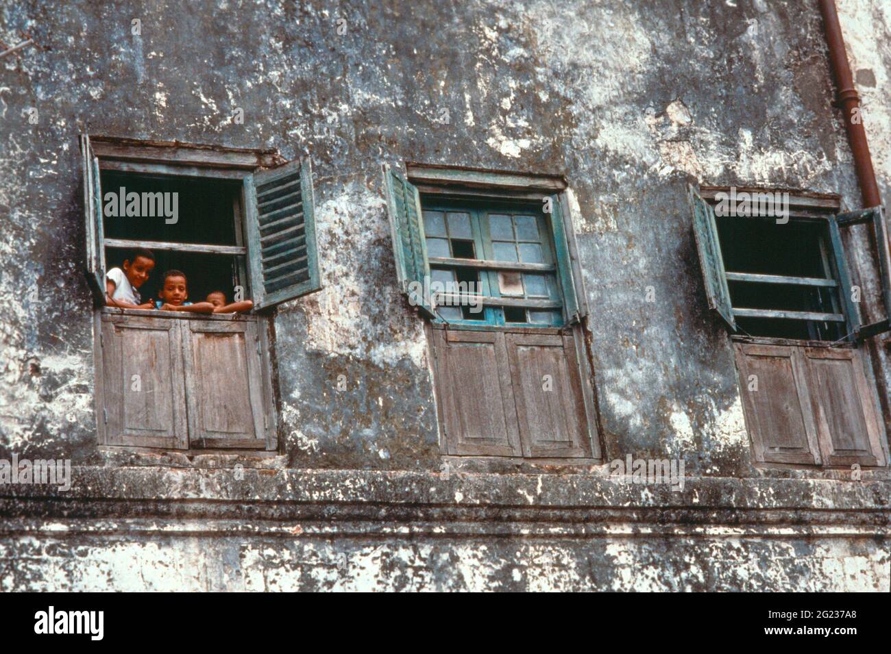 Enfants regardant par une fenêtre d'un vieux bâtiment à Stone Town, Zanzibar, Tanzanie Banque D'Images