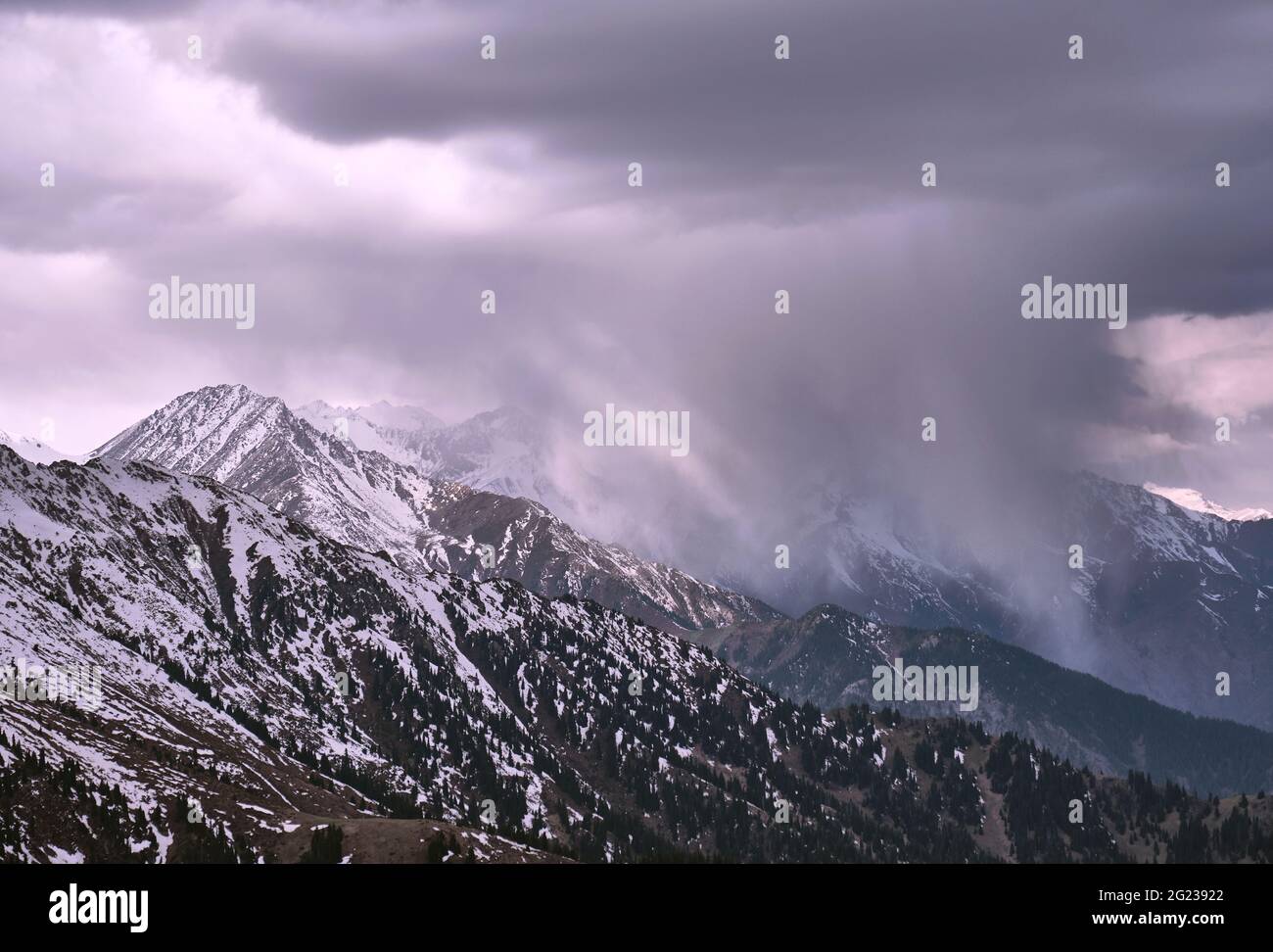 Des nuages de neige spectaculaires dans une gorge de montagne illuminés par la lumière douce du soleil du matin; des phénomènes naturels étonnants, le temps qui s'aggrave, l'approa Banque D'Images