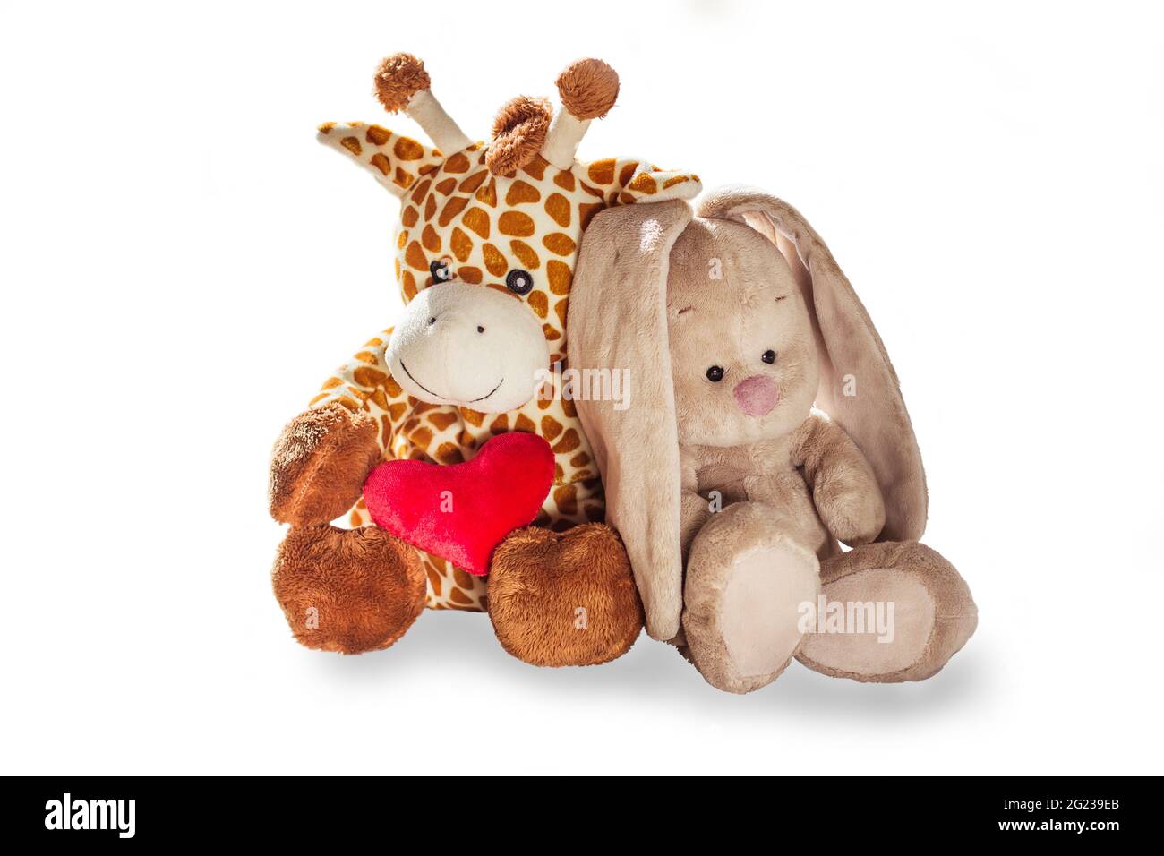 Peluche girafe jouet et lapin tient un coeur rouge isolé sur un fond blanc jouet coloré peluche. Girafe et lapin en peluche de couleur. Blanc an Banque D'Images