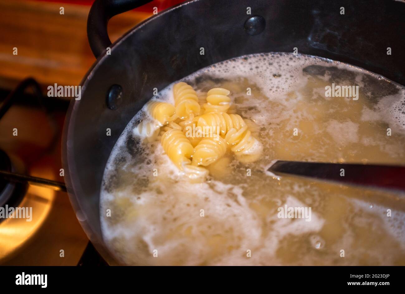 Cuisson de pâtes séchées dans de l'eau bouillante et vidange Banque D'Images