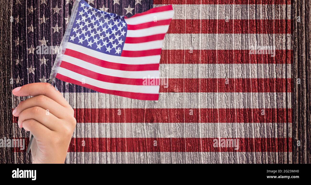 Main tenant un drapeau américain contre nous drapeau sur fond de bois Banque D'Images