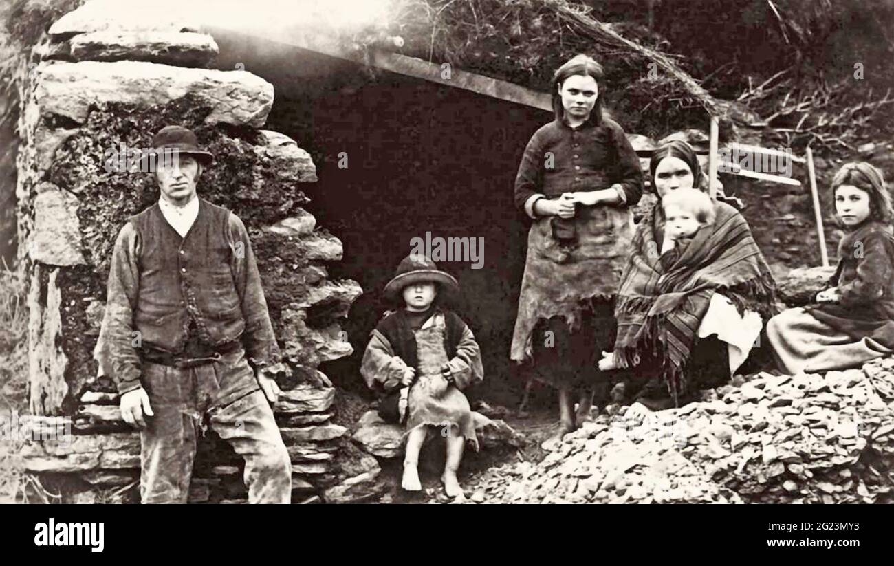 PAUVRE FAMILLE IRLANDAISE. Une famille touchée par la pauvreté en dehors de leur maison en manille à Killarney, dans le sud-ouest de l'Irlande, vers 1890. Photo: Graphic House Archive Banque D'Images