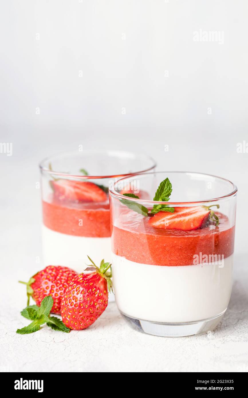 Panna cotta en verres avec sauce fraise et menthe. Banque D'Images