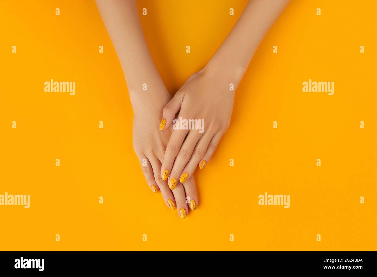 Femmes manucures avec un motif à ongles tendance sur fond orange Banque D'Images