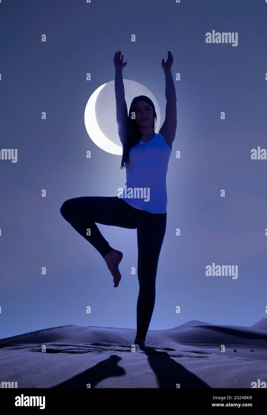 Dubaï, Émirats arabes Unis, femme pratiquant le yoga sur une dune de sable dans le désert la nuit Banque D'Images