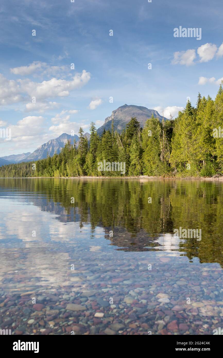 Belles montagnes se reflétant dans le lac McDonald avec des galets en premier plan. Parc national des Glaciers, Montana Banque D'Images