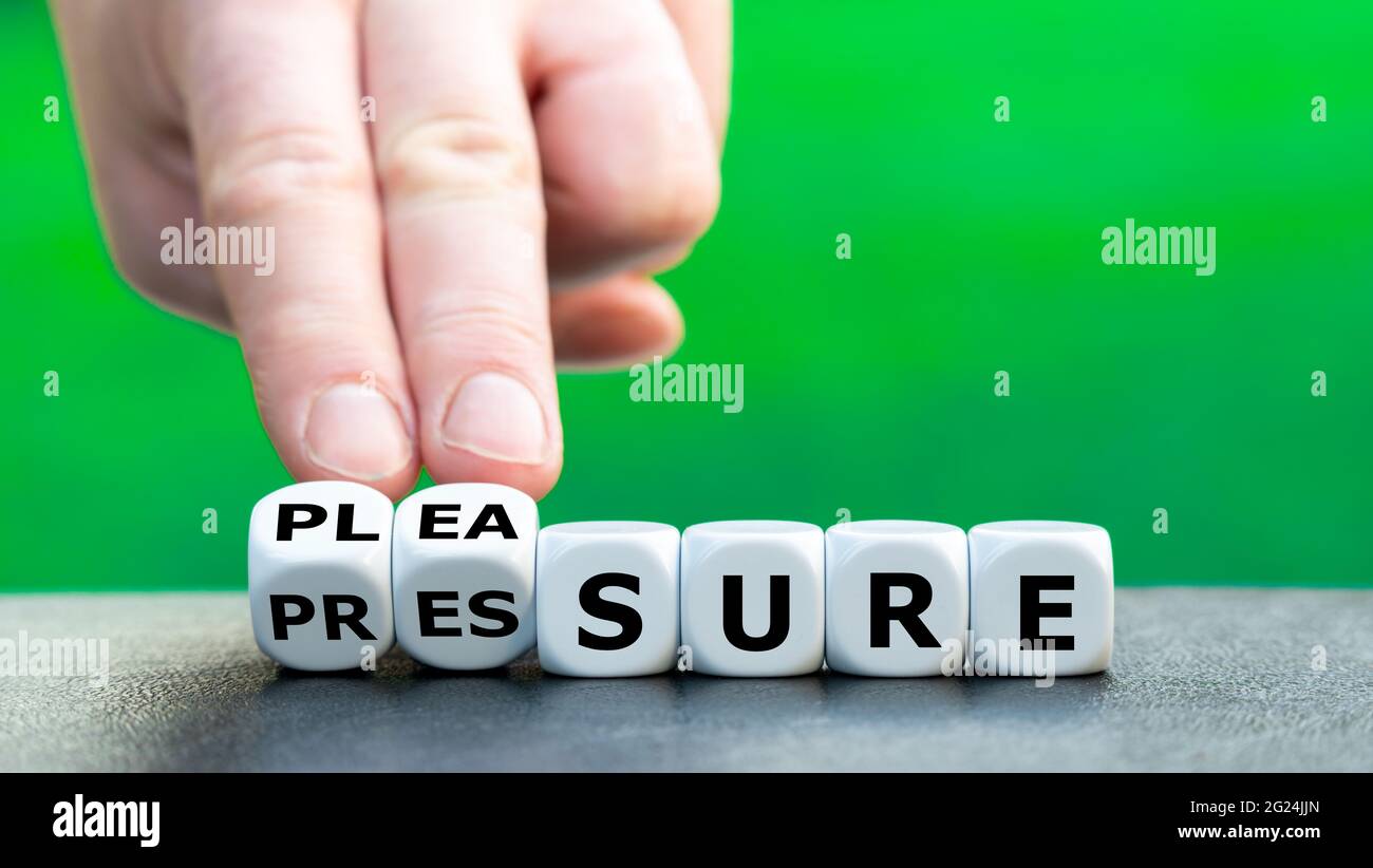 La main tourne les dés et change le mot « pression » en « plaisir ». Banque D'Images