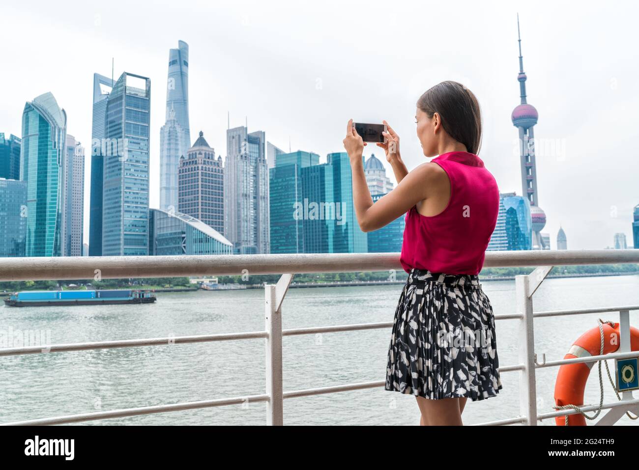 Femme asiatique prenant une photo de téléphone sur le ferry de Shanghai Banque D'Images