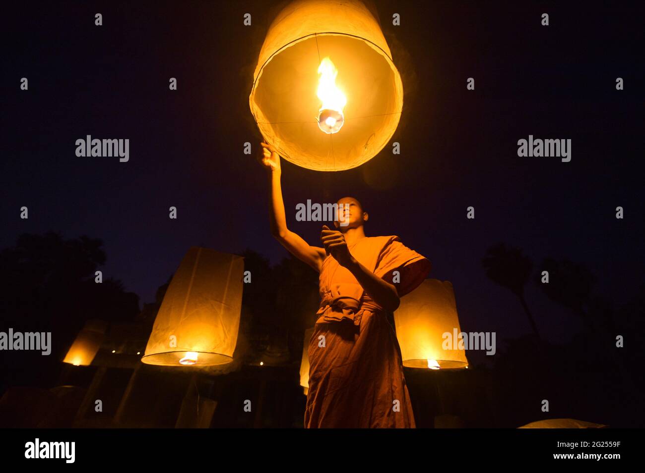 Monk bouddhiste libérant des lanternes dans le ciel la nuit, Thaïlande Banque D'Images