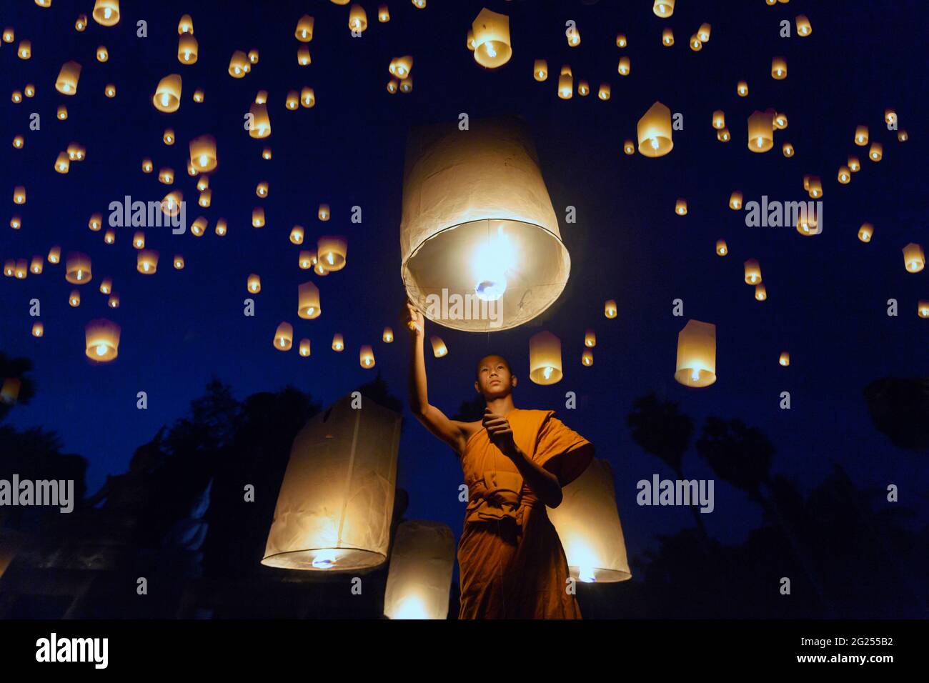 Monk bouddhiste libérant des lanternes dans le ciel la nuit, Thaïlande Banque D'Images