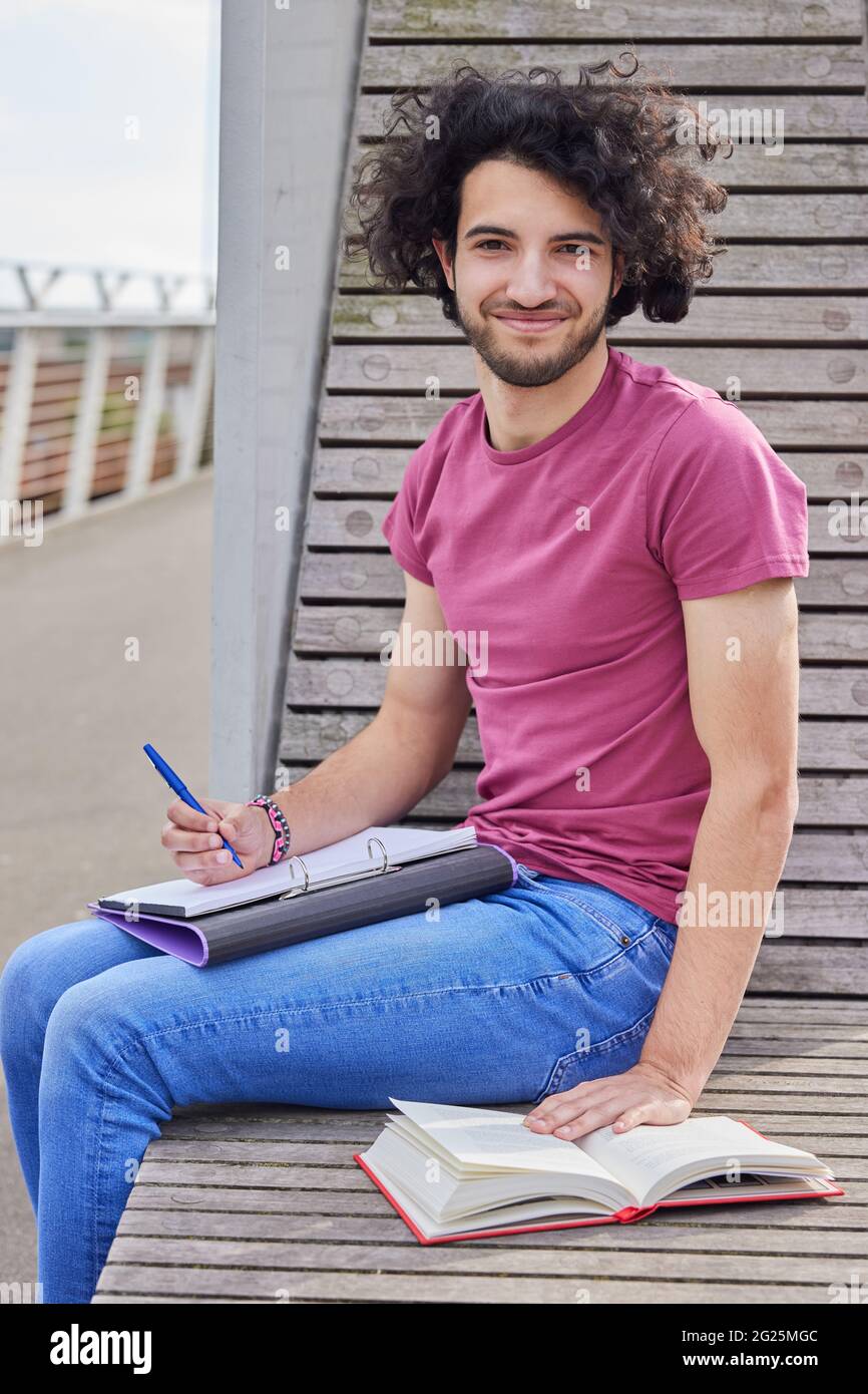 Portrait de confiant, jeune étudiant de collège masculin travaillant à l'extérieur sur le campus de collège Banque D'Images