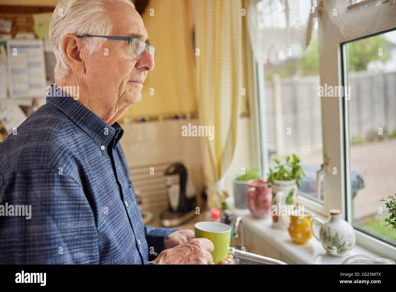 Homme solitaire senior qui a l'air mécontent de la coupe de la fenêtre Banque D'Images