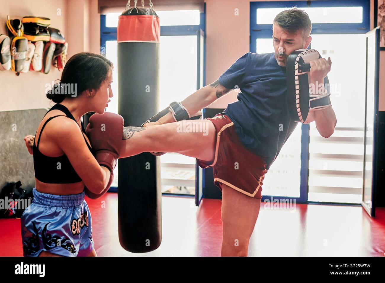 Une jeune femme s'entraîne avec son entraîneur Muay Thai dans une salle de sport Banque D'Images