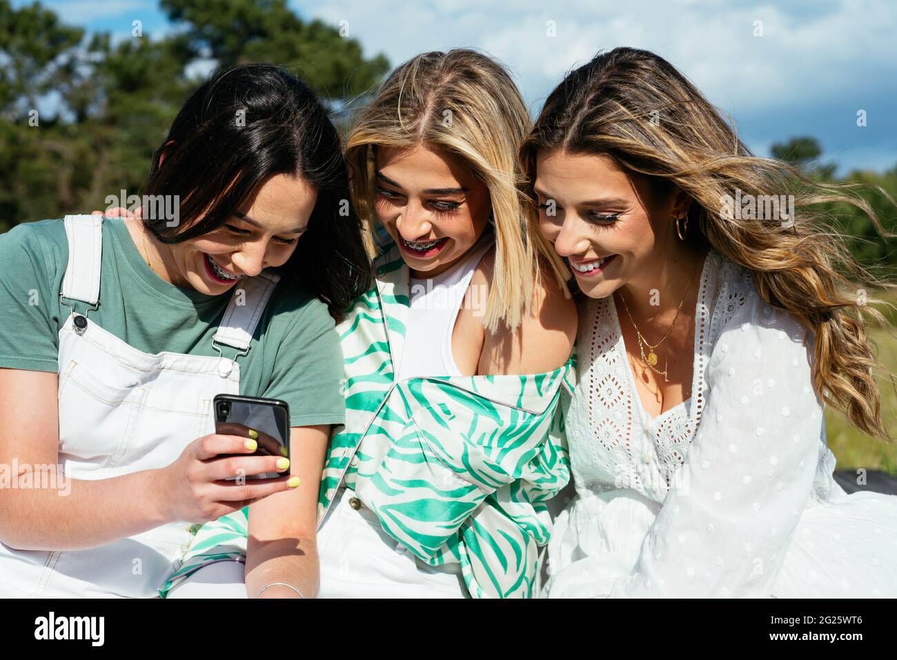 Trois amies qui utilisent un téléphone portable et qui s'amusent Banque D'Images