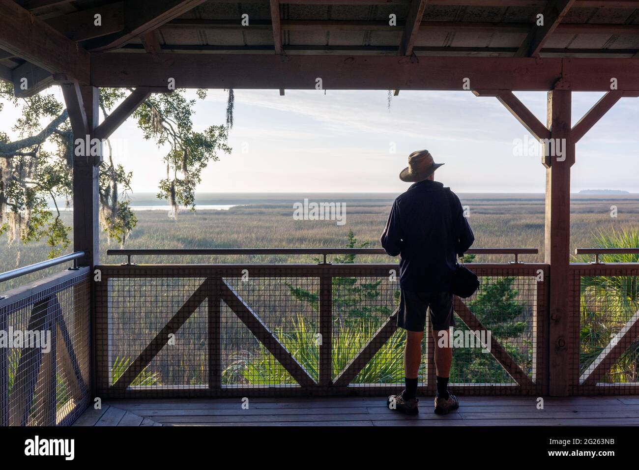 Un homme âgé sur une grande véranda prend dans le magnifique paysage d'un marais salé de lowcountry près de l'île de Sapelo, côte de Géorgie, Etats-Unis. Banque D'Images