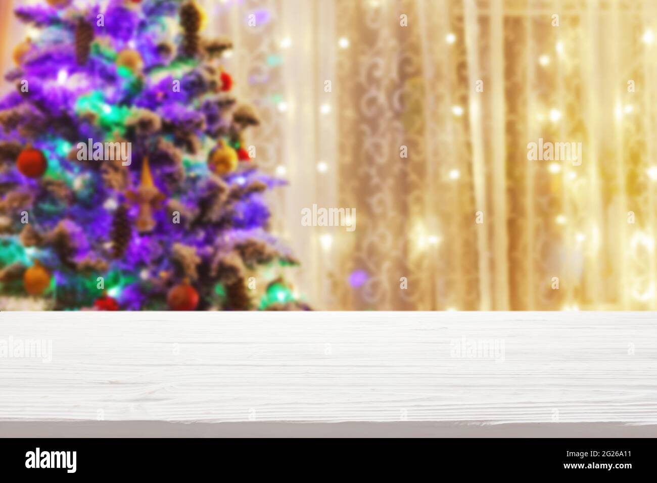 plateau de table en bois blanc sur un arbre de noël flou avec arrière-plan guirlande Banque D'Images