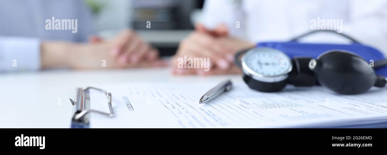 Tonomètre et presse-papiers avec antécédents médicaux à proximité de la table médecin et patient Banque D'Images
