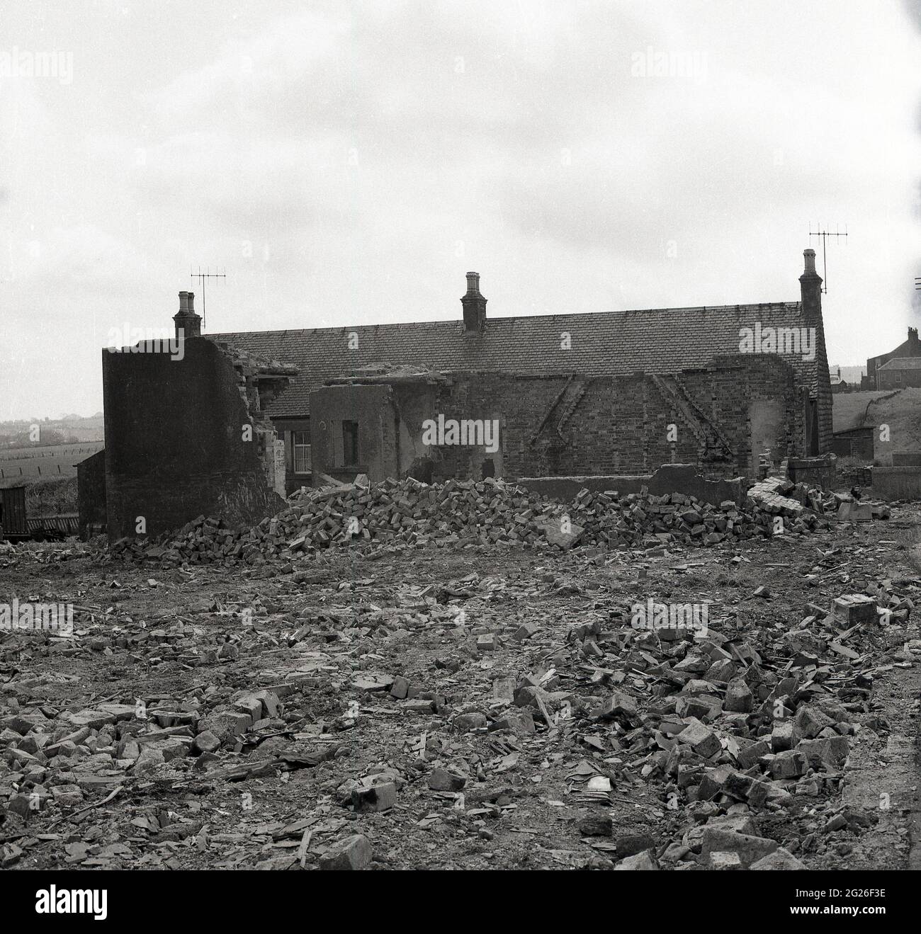 Années 1960 historique, vieilles briques, la maçonnerie et les décombres de construction sur le sol derrière un ancien cottage abandonné dans le village de Kelty, Fife, Écosse, Royaume-Uni. Un village minier de charbon sur la frontière de Fife et de Perthshire, à cette époque, la région a connu un avenir incertain, car les mines de charbon, qui employaient autrefois la majorité des travailleurs locaux à partir de 1873, lorsque la première mine profonde, la mine Lindsey, a été coulé, étaient fermées ou abandonnées. Banque D'Images