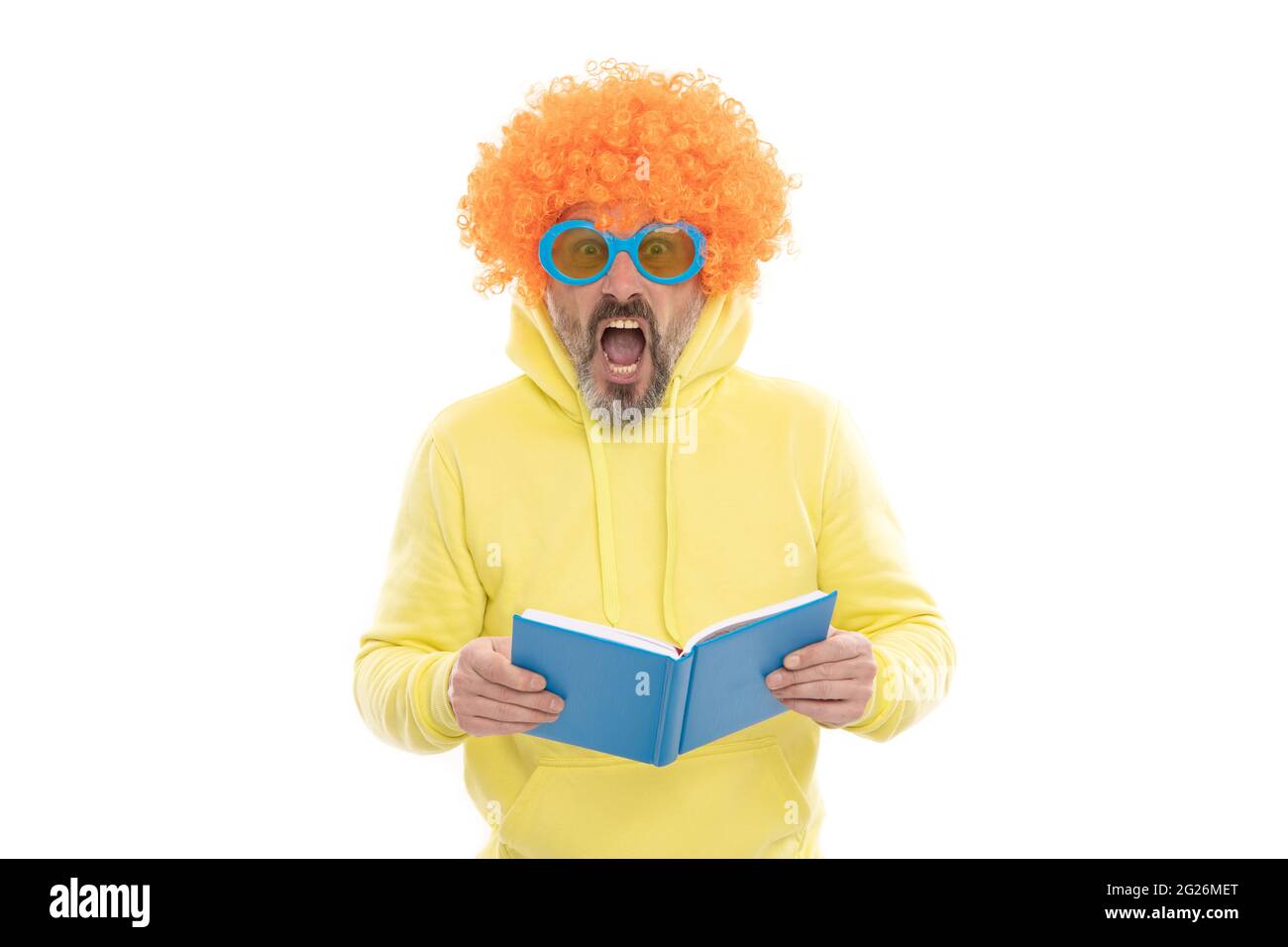 Geeky bibliophile dans la perruque funky garder la bouche ouverte lecture livre d'école, bibliothèque Banque D'Images