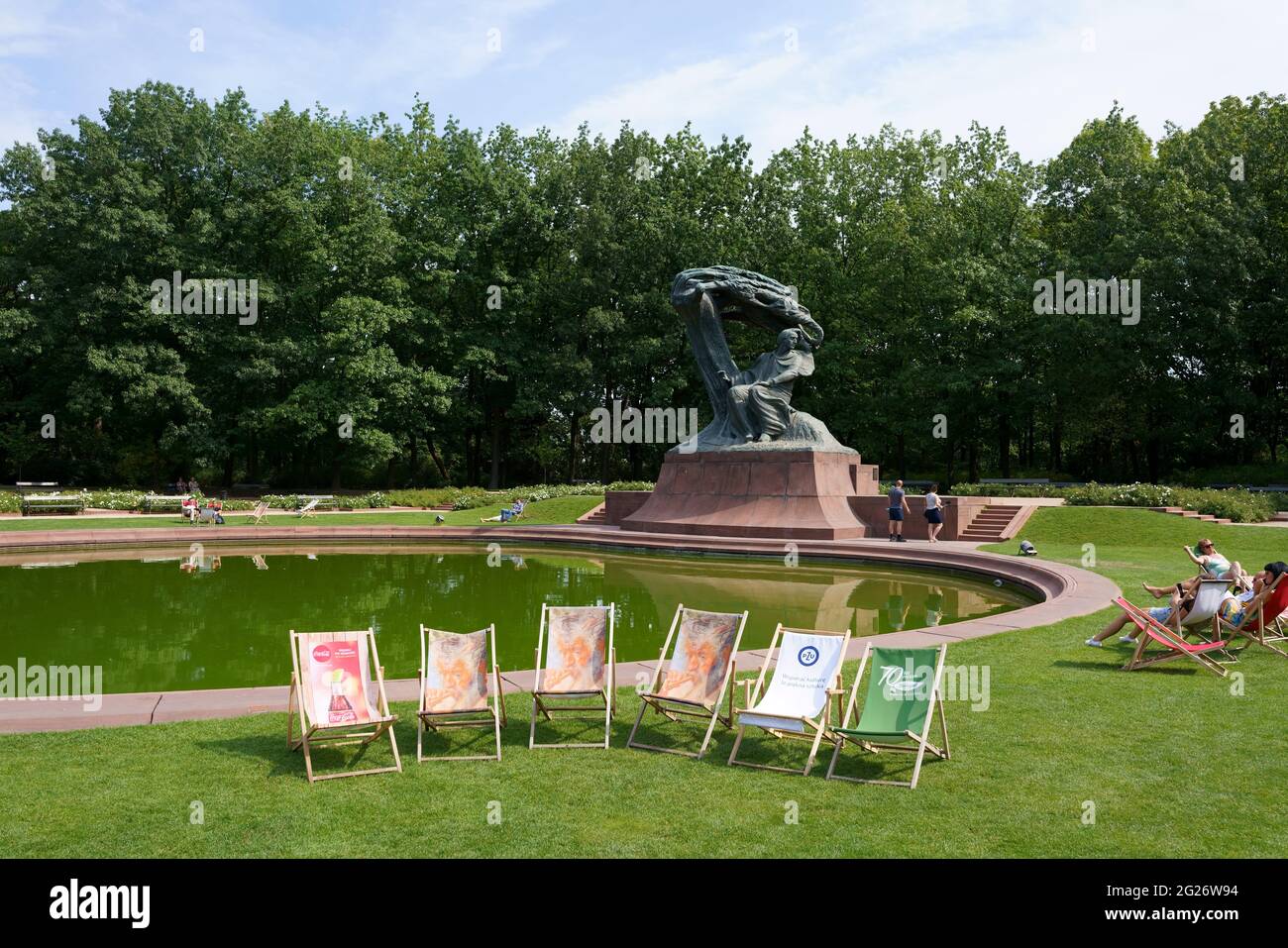 Des chaises de bureau vides et des personnes se reposent sur des chaises longues en face du monument Chopin dans le parc royal Lazienki à Varsovie, en Pologne Banque D'Images